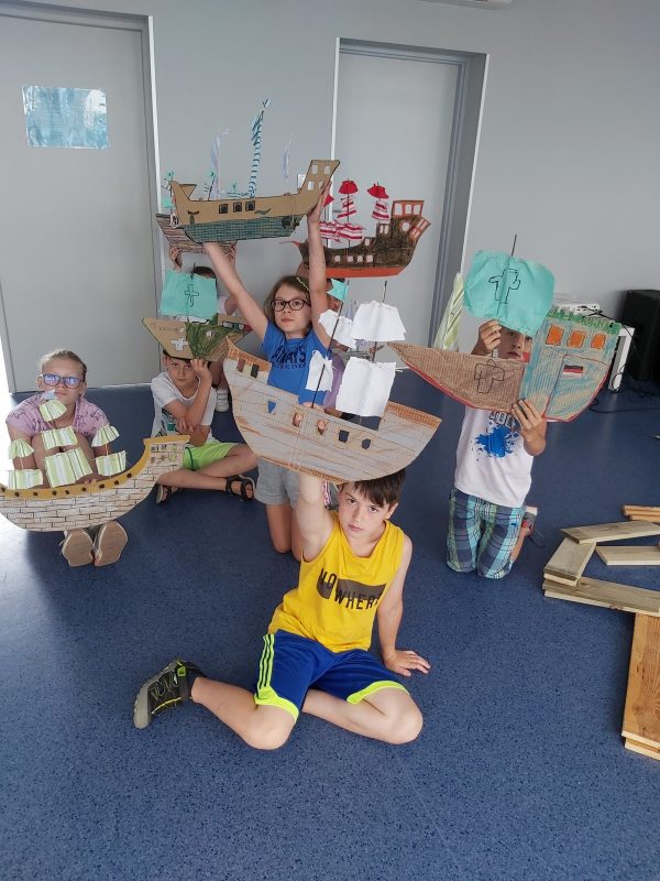 Dzieci pozują z wykonanymi okrętami z kartonu