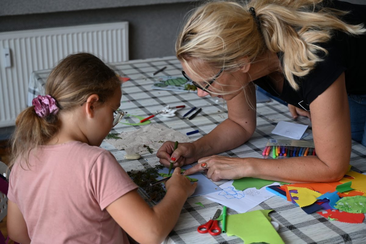 Kobieta pomaga dziewczynce malować pracę plastyczną